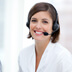 Customer service agent in white blouse smiling at the camera wearing a headset.
