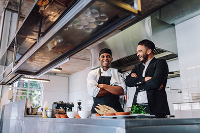 Smiling restaurant owner and chef standing in the restaurant’s kitchen.